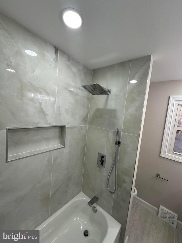 bathroom with toilet, baseboards, visible vents, and  shower combination