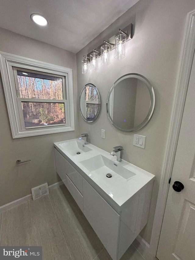 full bathroom with visible vents, a sink, baseboards, and double vanity