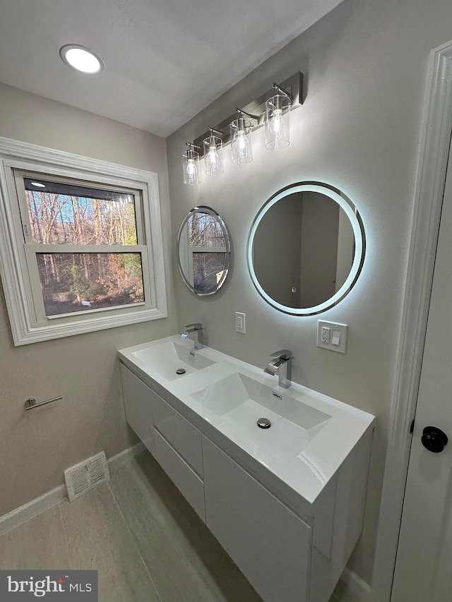 bathroom featuring visible vents, a sink, baseboards, and double vanity