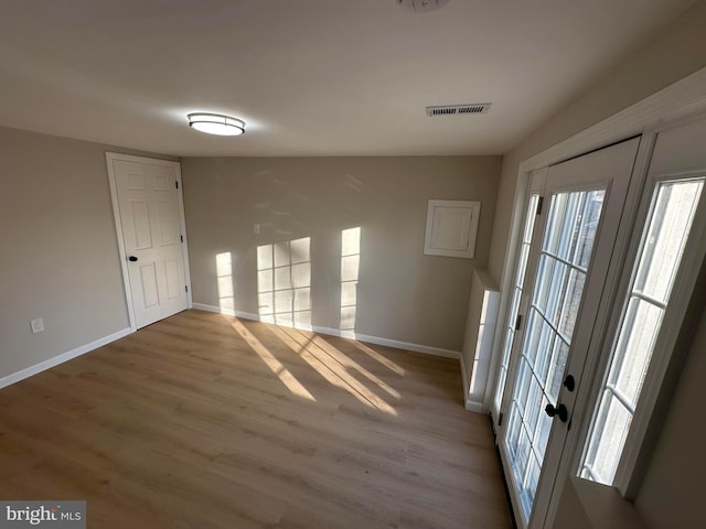 unfurnished room featuring wood finished floors, visible vents, and baseboards