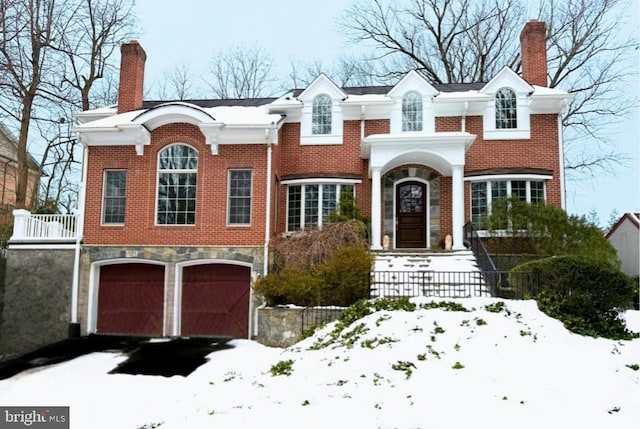 view of front facade featuring a chimney, aphalt driveway, and brick siding