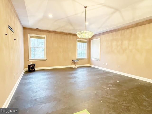 unfurnished room with visible vents, an inviting chandelier, a wealth of natural light, and baseboards