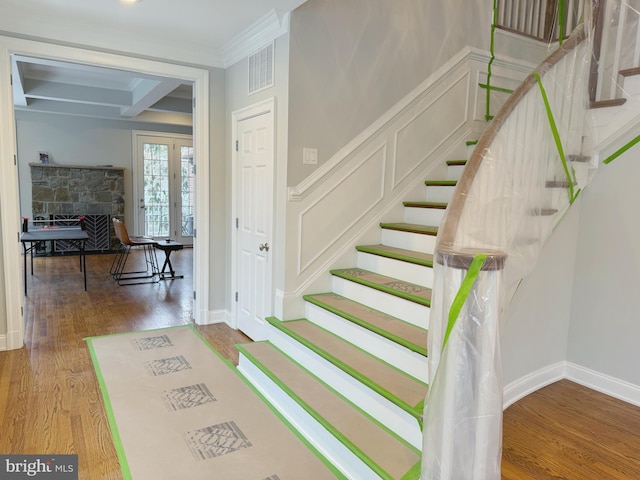 stairway with visible vents, ornamental molding, wood finished floors, beamed ceiling, and baseboards