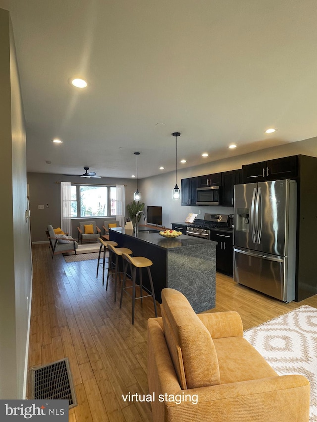 kitchen with appliances with stainless steel finishes, dark cabinetry, recessed lighting, open floor plan, and visible vents