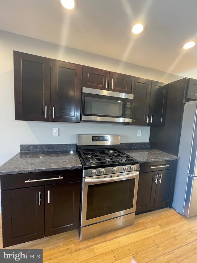 kitchen with recessed lighting, light wood finished floors, dark stone countertops, and stainless steel appliances
