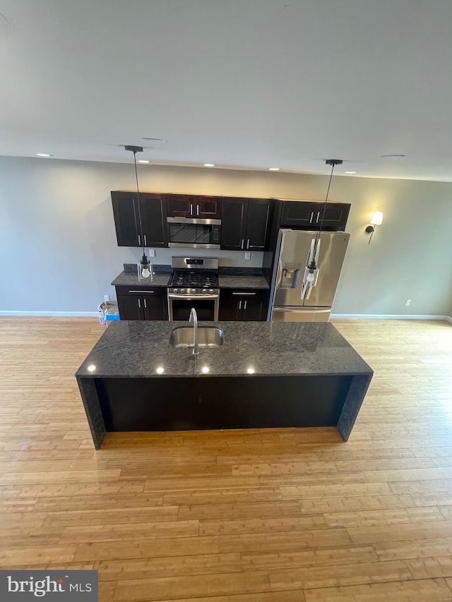 kitchen with hanging light fixtures, light wood-type flooring, a sink, baseboards, and stainless steel appliances