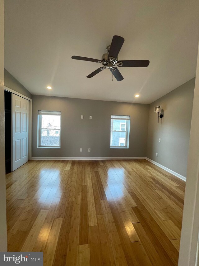 unfurnished room with baseboards, a ceiling fan, light wood-style flooring, and a wealth of natural light