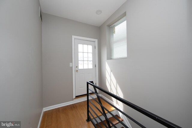 doorway featuring plenty of natural light, light wood finished floors, and baseboards