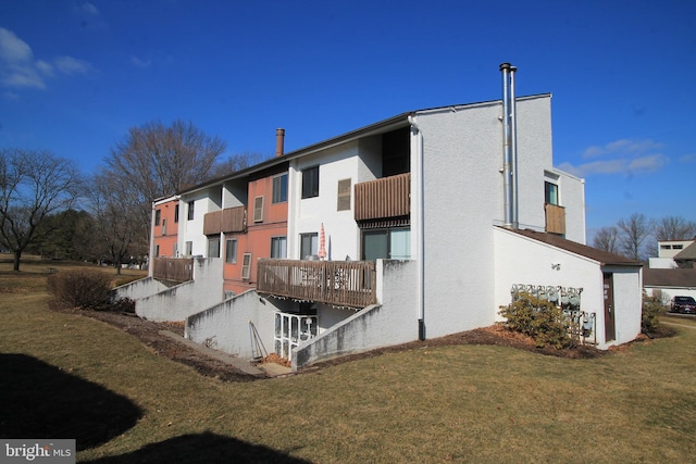 rear view of house featuring a yard and stucco siding