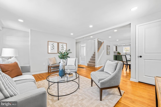 living area featuring light wood finished floors, stairs, baseboards, and recessed lighting