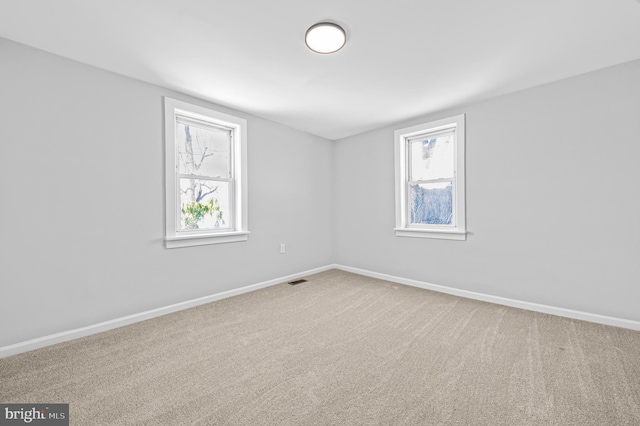 unfurnished room with carpet flooring, visible vents, and baseboards