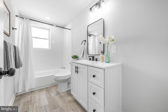 bathroom with toilet, wood finished floors, shower / bath combination with curtain, and vanity