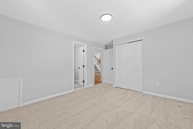 unfurnished bedroom with light carpet, baseboards, and a closet