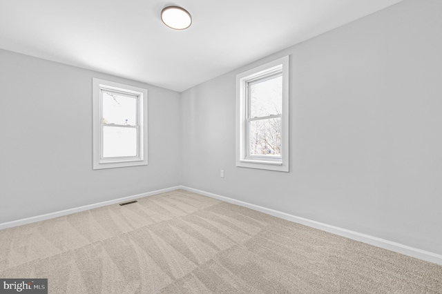 spare room featuring light carpet, visible vents, and baseboards