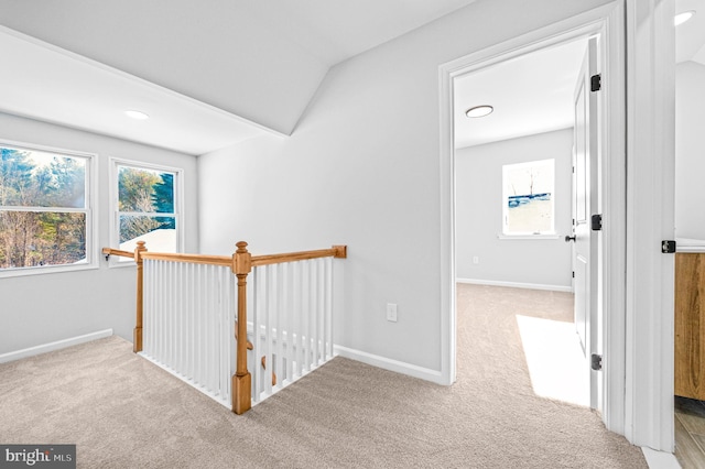 hall with an upstairs landing, light carpet, and baseboards