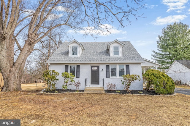 cape cod-style house featuring a shingled roof and entry steps