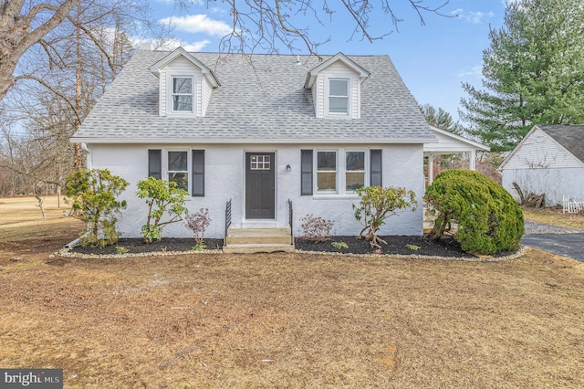 cape cod house featuring a shingled roof, entry steps, and stucco siding