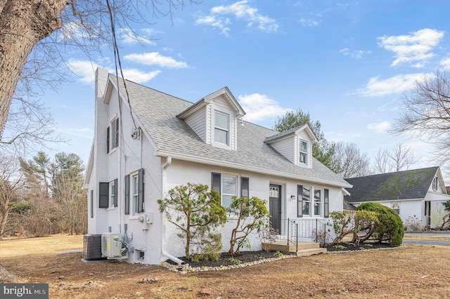 cape cod house featuring central air condition unit, roof with shingles, and stucco siding