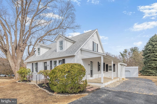 view of front of home featuring a porch, a shingled roof, an outdoor structure, and stucco siding