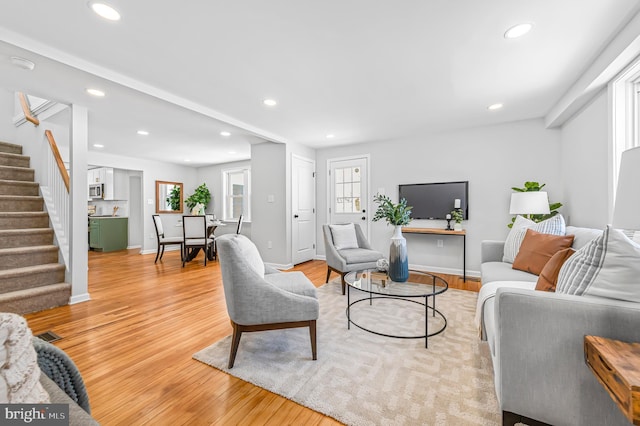 living area with baseboards, stairway, light wood-type flooring, and recessed lighting