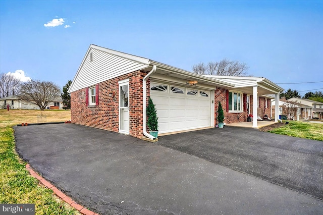 view of side of home with driveway, brick siding, and an attached garage