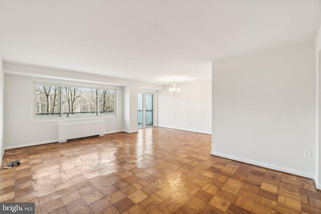 spare room with radiator, a notable chandelier, and baseboards