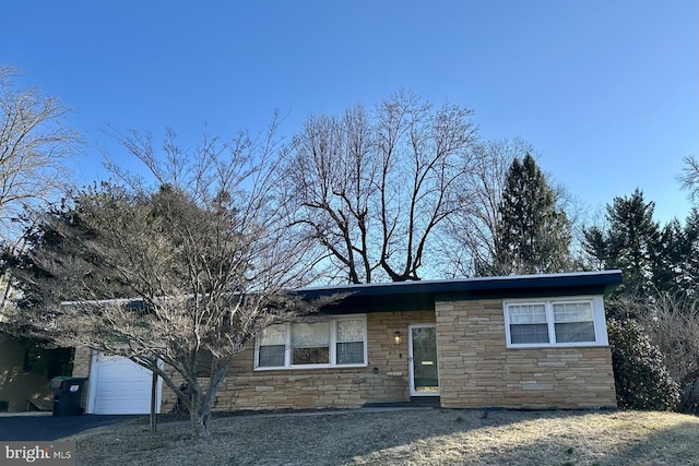 view of front of home with a garage, stone siding, and aphalt driveway