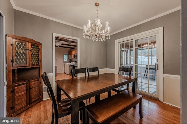 dining room with wainscoting, an inviting chandelier, wood finished floors, and crown molding