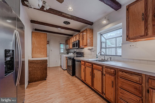 kitchen with stainless steel appliances, light countertops, brown cabinetry, a sink, and light wood-type flooring