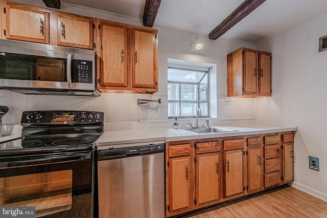 kitchen with a sink, appliances with stainless steel finishes, light countertops, and beam ceiling