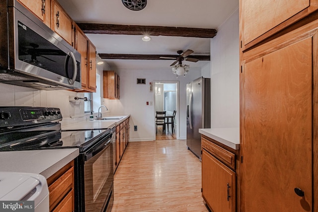 kitchen with brown cabinets, light countertops, appliances with stainless steel finishes, light wood-style floors, and a sink