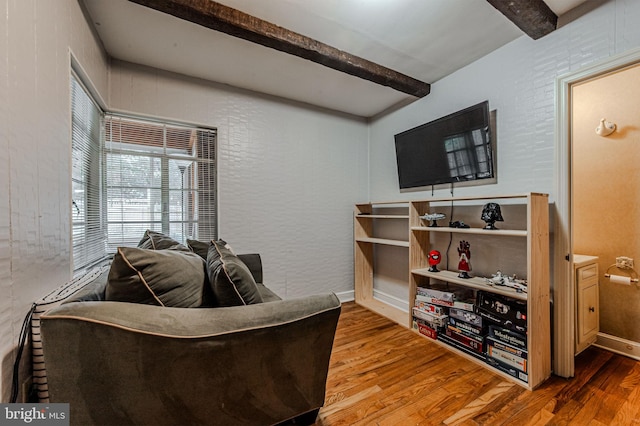 living room featuring wood finished floors, beam ceiling, and baseboards