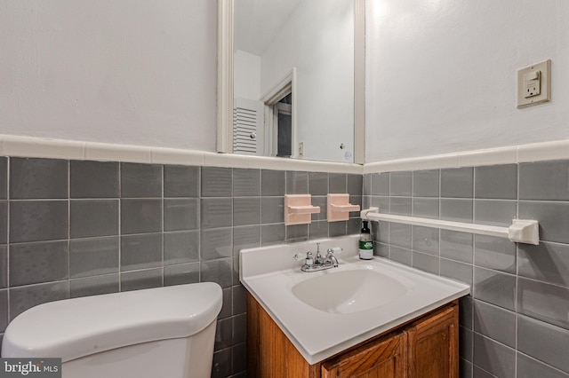 bathroom with tile walls, vanity, and toilet