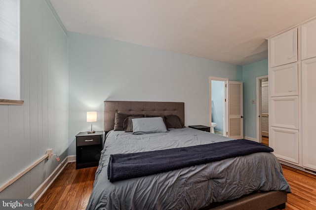 bedroom with ensuite bath, baseboards, and wood finished floors