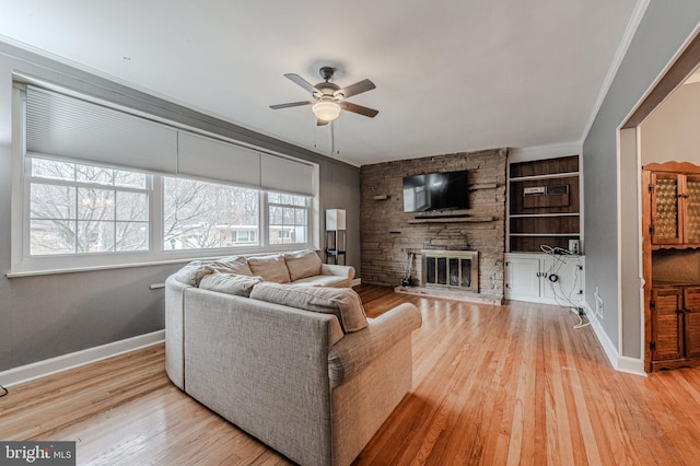 living room featuring built in features, ceiling fan, a stone fireplace, wood finished floors, and baseboards