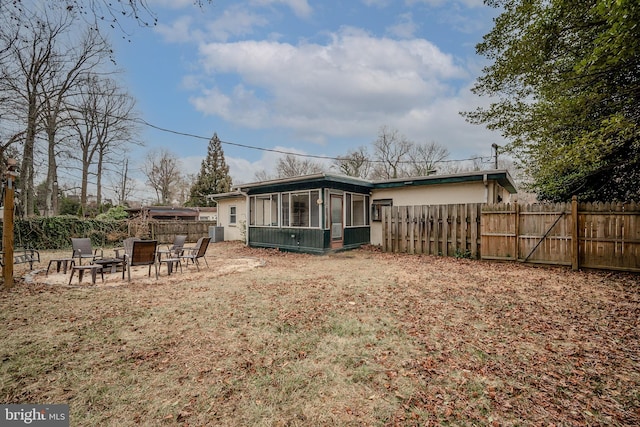 rear view of house with a fire pit, fence, and a sunroom