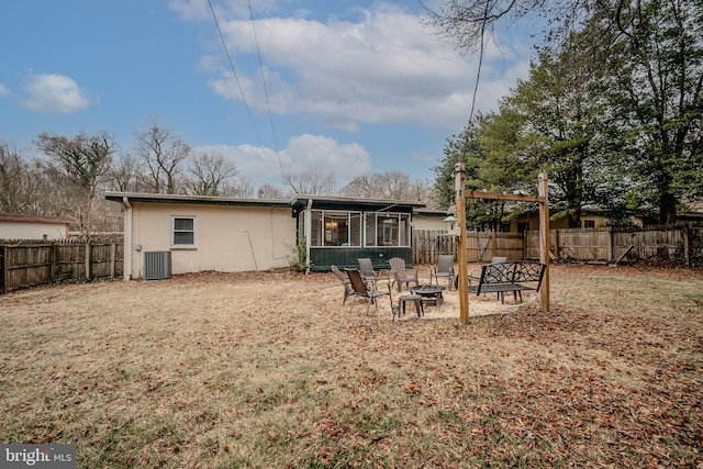 back of house with stucco siding, an outdoor fire pit, a sunroom, central AC, and a fenced backyard