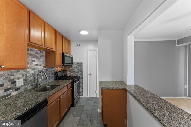 kitchen featuring a sink, appliances with stainless steel finishes, brown cabinets, tasteful backsplash, and dark stone countertops