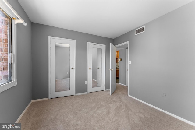 unfurnished bedroom featuring baseboards, visible vents, and light colored carpet