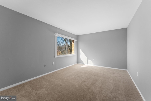 carpeted empty room featuring baseboards