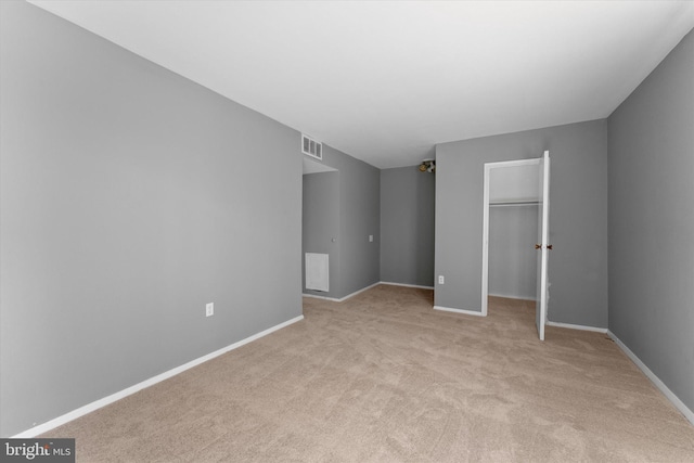 unfurnished bedroom with light carpet, a spacious closet, a closet, and baseboards