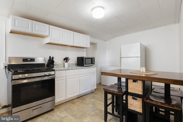 kitchen with appliances with stainless steel finishes, white cabinetry, and light stone counters