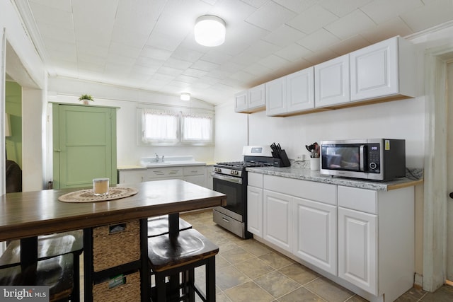 kitchen with lofted ceiling, stainless steel appliances, light countertops, and white cabinets