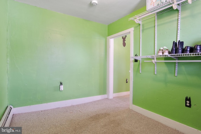 carpeted empty room with a baseboard radiator and baseboards