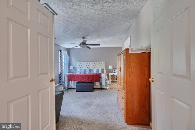 carpeted bedroom featuring ceiling fan and a textured ceiling