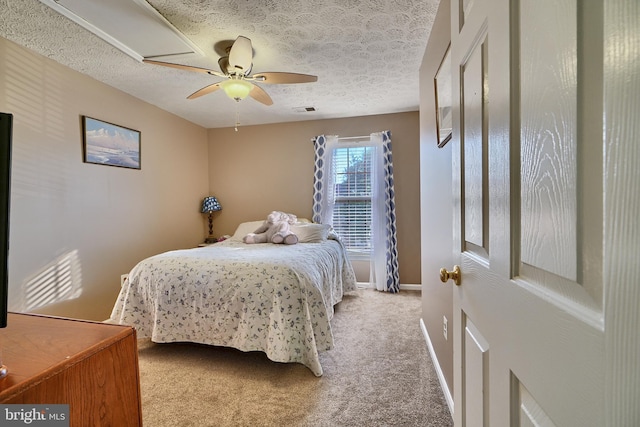 carpeted bedroom with a textured ceiling, visible vents, a ceiling fan, and baseboards