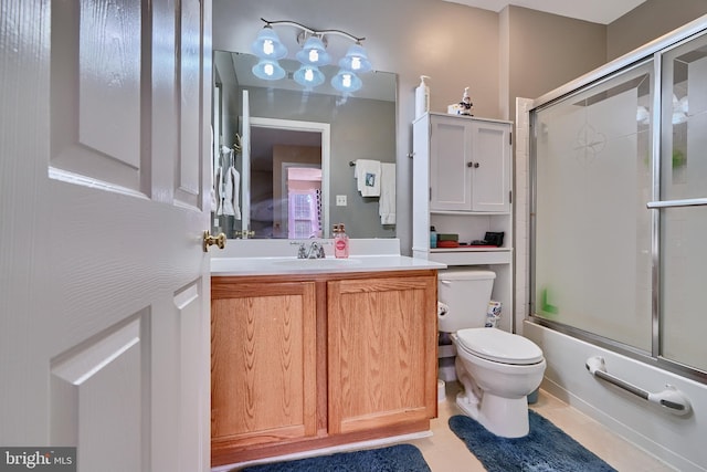 full bathroom featuring shower / bath combination with glass door, tile patterned flooring, vanity, and toilet