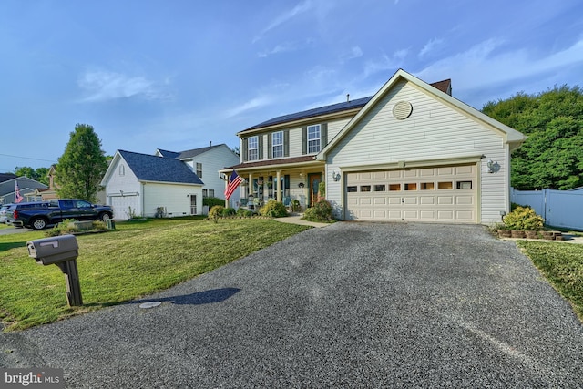 traditional home featuring aphalt driveway, a garage, covered porch, fence, and a front yard