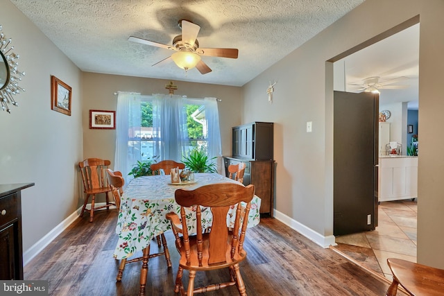 dining space featuring baseboards, a textured ceiling, a ceiling fan, and wood finished floors