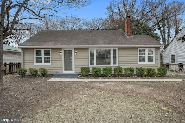 ranch-style home featuring roof with shingles, a chimney, and fence